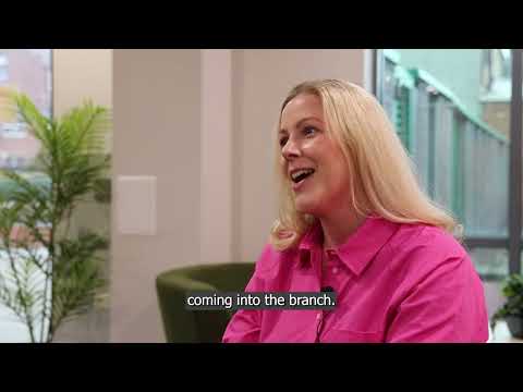 A still from a cyber security video, showing a woman wearing a pink shirt with blonde hair.